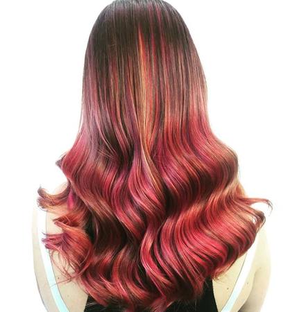 Lange, gewellte Haare in leuchtendem Rot mit sanften Farbverläufen und Balayage-Effekt.