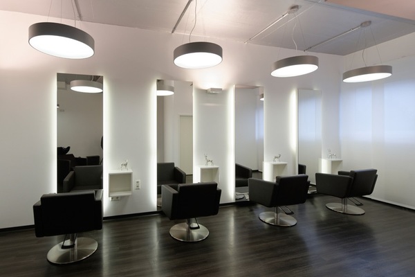 Moderner Friseursalon mit vier Stylingplätzen, Spiegeln und eleganten schwarzen Stühlen.