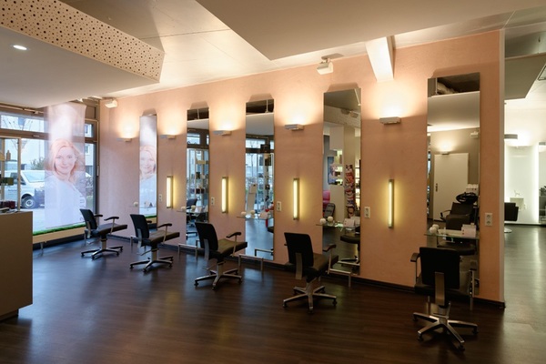 Moderner Friseursalon mit sechs Stylingplätzen, großen Spiegeln und hellen Wandlampen.