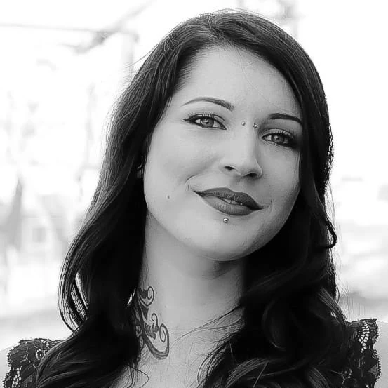 Schwarzweiß-Porträt einer Frau mit Piercings, Tattoo und langen Haaren